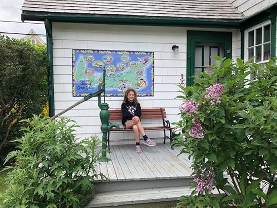 A girl sitting on a bench in front of an Anne of Green Gables map of PEI