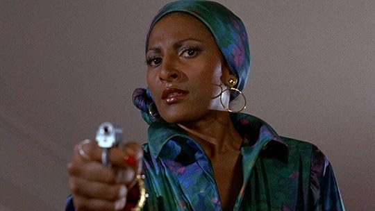 Pam Grier, in aquamarine, holds a gun in Foxy Brown (1974)