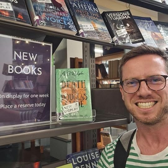 Author G B Ralph selfie with Death in Douglas Glade paperback on the New Books shelf at the library