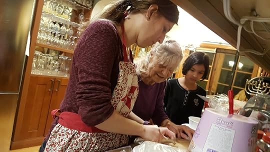 Two women, one in her 70s, one in her 30s, cook alongside a little girl. 