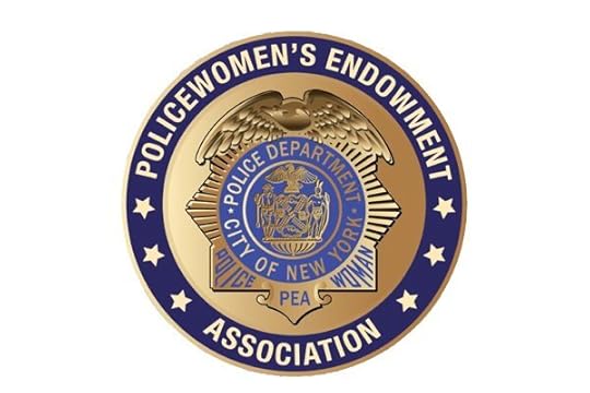 A gold police badge featuring a prominent blue circle. The blue circle contains the text 