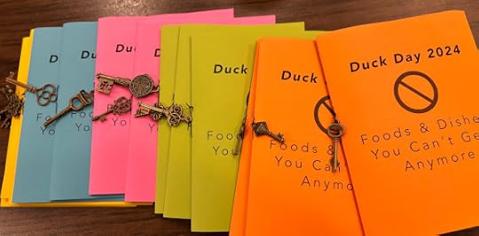 Bright colored booklets that say Duck Day 2024 with a small brass key dangling from each one. 
