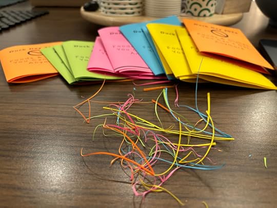 Brightly colored paper folded into booklets with brightly colored scrap trimmings 