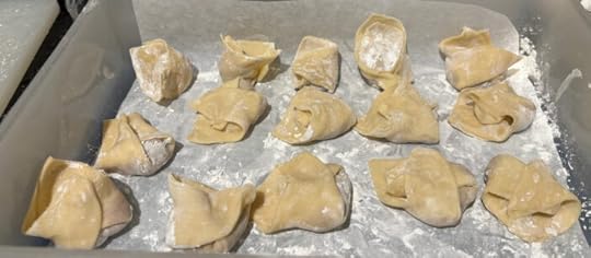 Uncooked wontons arranged in rows on parchment paper