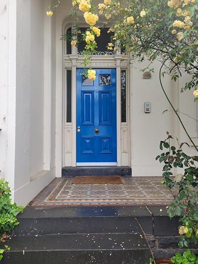 Blue door in terrace house with yellow roses in front