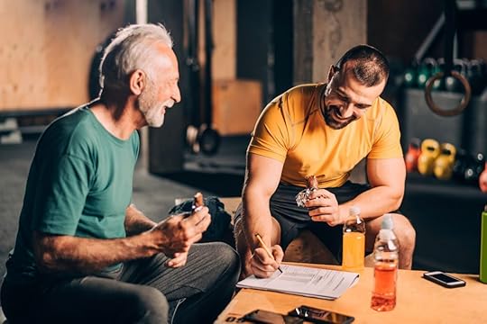 A nutrition coach reviews a checklist with a client who is eating a protein bar after a workout.