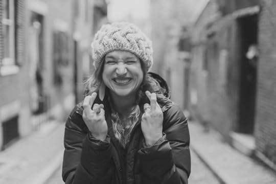 Woman with fingers crossed and a determined look on her face. Positivity and positive thinking are not the same.