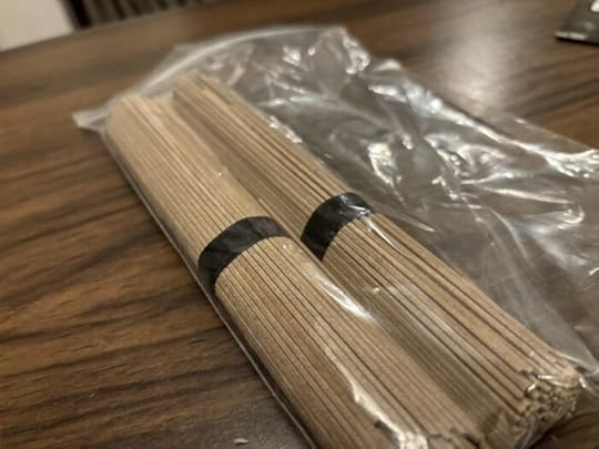 Two bundles of long straight brown noodles, banded with band paper bands. 