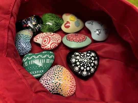 An assortment of colorfully painted hearts on a red satin background.