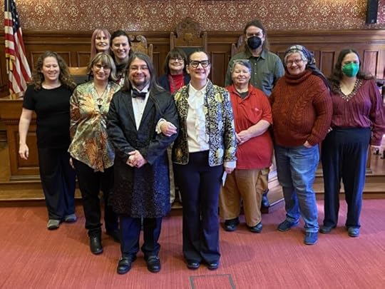 Group of 11 people posing for a photo inside the main city council chamber of Cambridge
