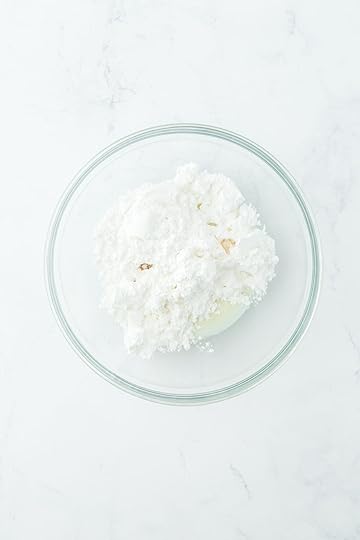 A bowl of powdered sugar, milk and extracts ready for mixing