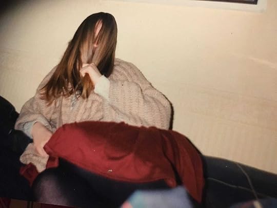 A picture of me as a teenager, hiding behind my hair, wearing a woolly cardy and red dress