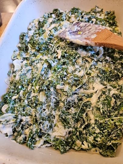 The creamy kale mixture being spread into the baking dish