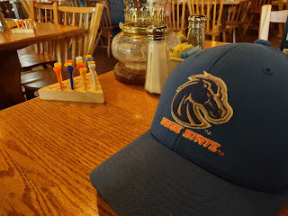 Image of a blue cap with words Boise State and a horse head logoon it. Cap is on a table, alongside salt and pepper shakers