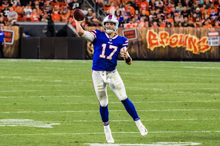 Football player for the Buffalo Bills, wearing white pants, blue jersey (number 17), and helmet. Player is ready to throw a ball