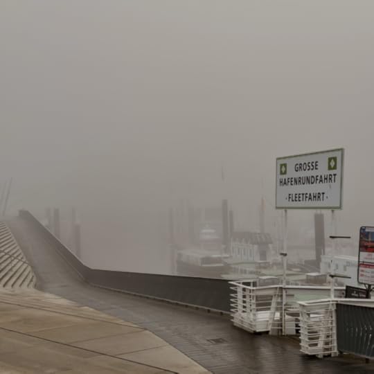 Die Hamburger Hafenpromenade im dichten Nebel, an der Kaimauer ein Schild 