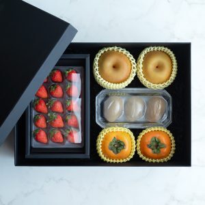 Black gift box filled with luxury Japanese strawberries, Asian pears, kiwirfruit, and persimmons
