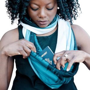 African American woman wearing a black top and tucking a passport into the secret pocket of a woodland-print scarf
