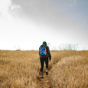 Person walking on trail with small daypack. Image: GetStencil