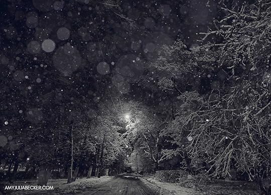 a black and white photo of a snowy road at night