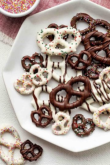plate of various chocolate covered pretzels including some with white chocolate, chocolate drizzles, and sprinkles.