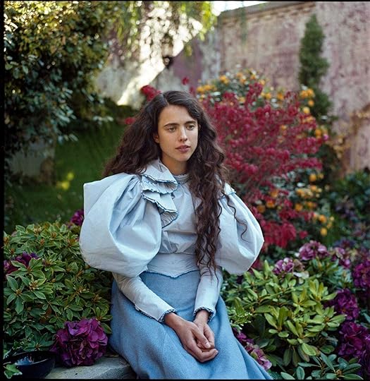 Margaret Qualley sits in a blue dress in