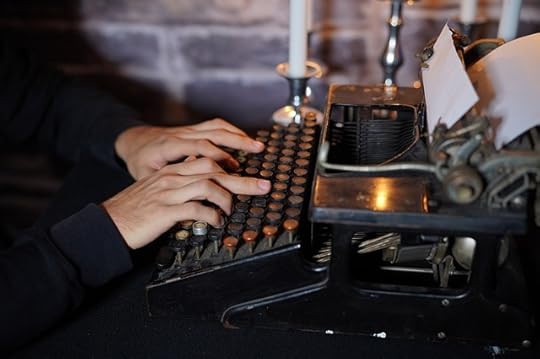 Manual typewriter with paper in it, and peron typing with two middle fingers.