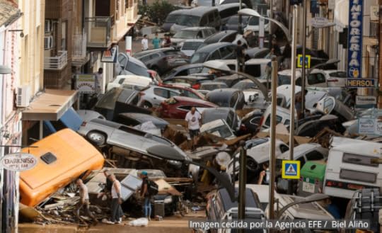Photo of a street filled with cars washed up and destroyed in a flood.