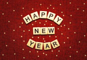 Happy New Year in Scrabble tiles against a red background.