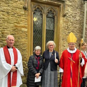 photo of Debbie holding candle, with parish priest, churchwarden and Bishop of Tewkesbury