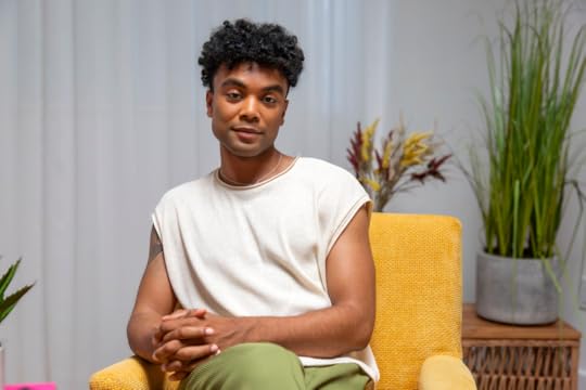 A man sits with his hands folded on his crossed knees