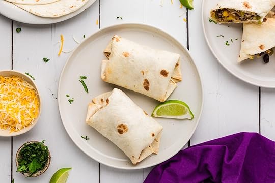Rice, Corn and Black Bean Burritos on a plate with fixings around it