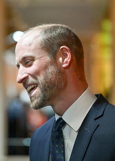 Prince William is seen in profile. He has a scruffy beard and is wearing a suit.
