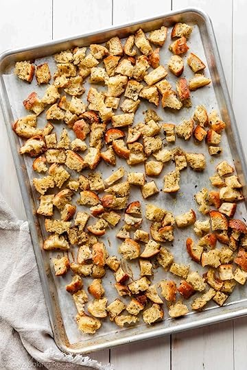 homemade baked croutons spread on lined baking sheet.