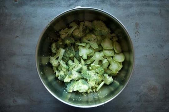 Broccoli florets and bits of cut stem in a metal mixing bowl