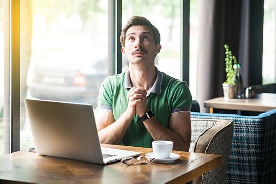 Man working on a laptop with hands crossed asking for foregiveness