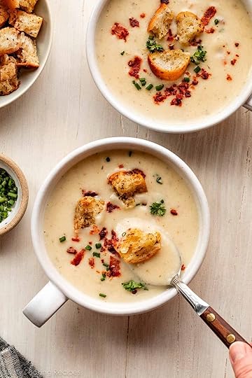 2 bowls of cauliflower potato soup with croutons, bacon, and chopped chives on top.
