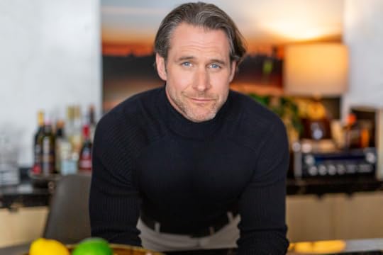 A man in a black turtleneck leans forward on a bar
