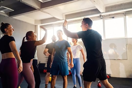 In a fitness class in an access gym, two clients exchange a high-five.