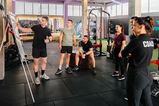 In an access gym, an expert fitness coach briefs group class participants at a whiteboard.