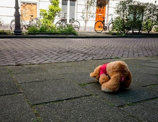 A teddy bear facedown on pavement, looking dejected. You can find positivity when it feels like it all sucks 