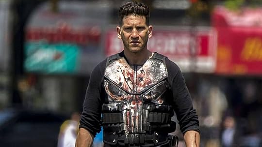 jon bernthal stands in the middle of street wearing bloody punisher vest