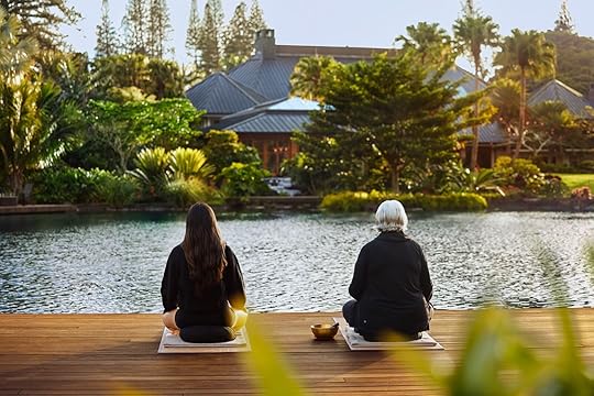 two people meditating near a pond