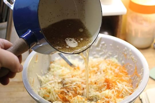 Pouring the health salad dressing over the prepared cabbage and carrots.