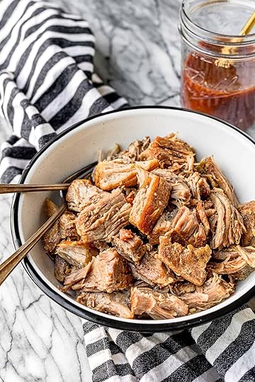 instant pot pulled pork in a black and white bowl with a black and white striped kitchen towel and jar of vinegar sauce