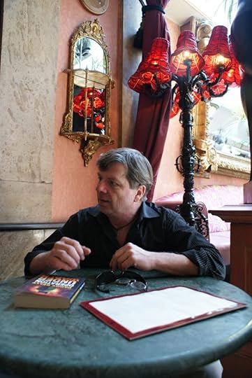 Paddy Kelly Writer Playwright sits at a desk with his books