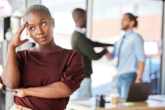 Woman rolling her eyes as two colleagues talk in the background