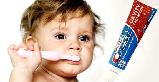 toddler brushing teeth and bottle of crest kids toothpaste