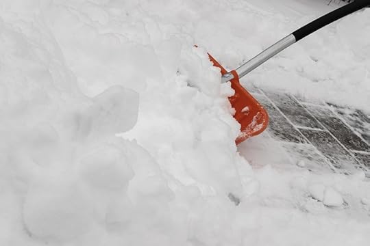 Red snow shovel clearing brick pavement.