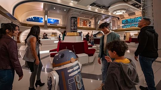 A kid talking to the droid SK-62O in the atrium of the Halcyon